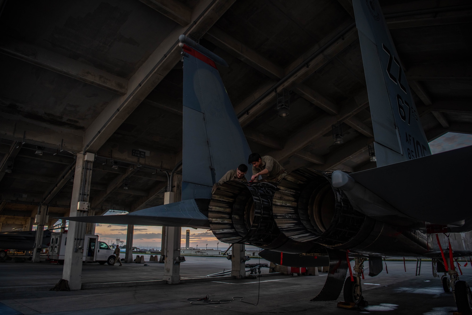 Airmen work on and around F-15C Eagles at sunset.