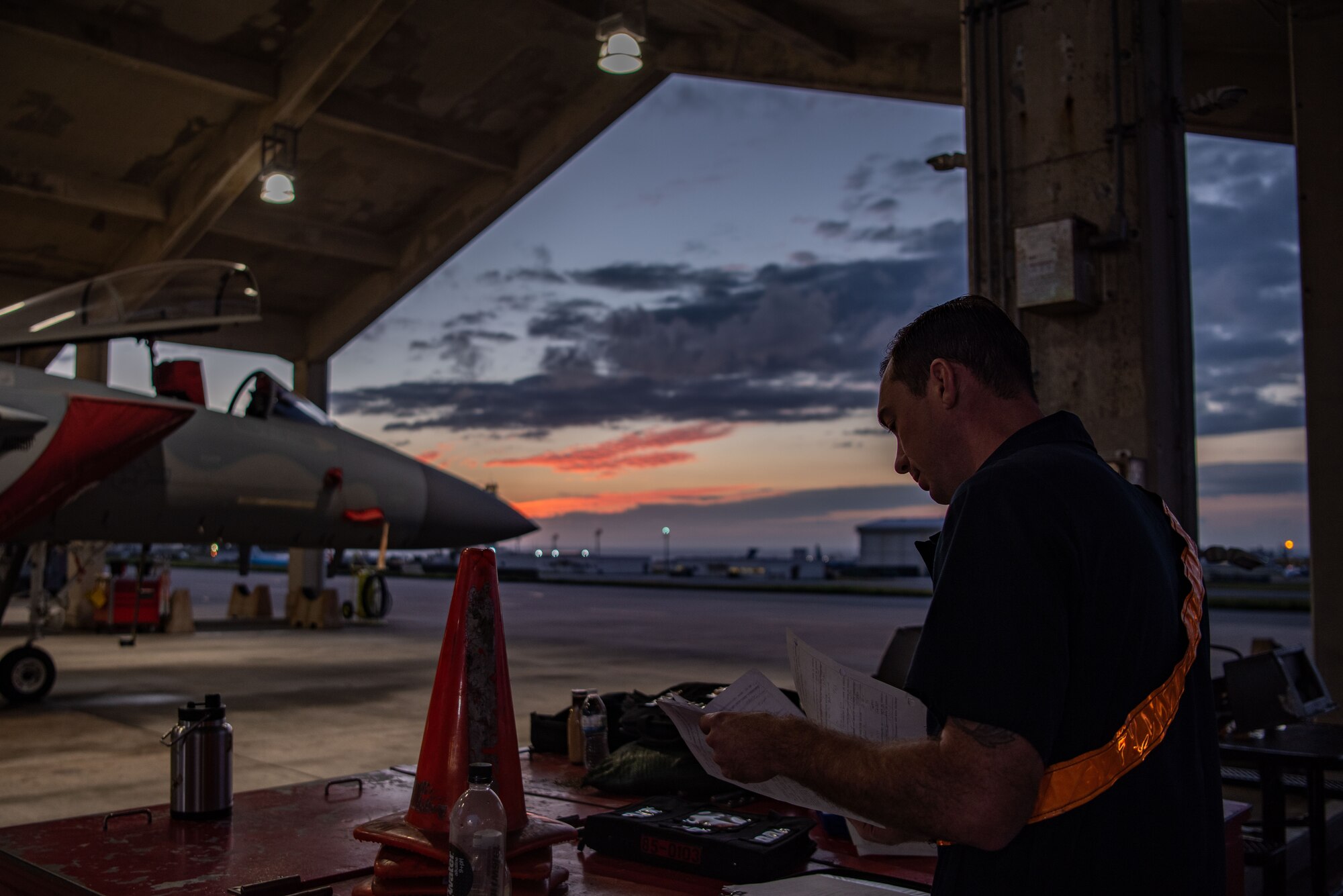 Airmen work on and around F-15C Eagles at sunset.