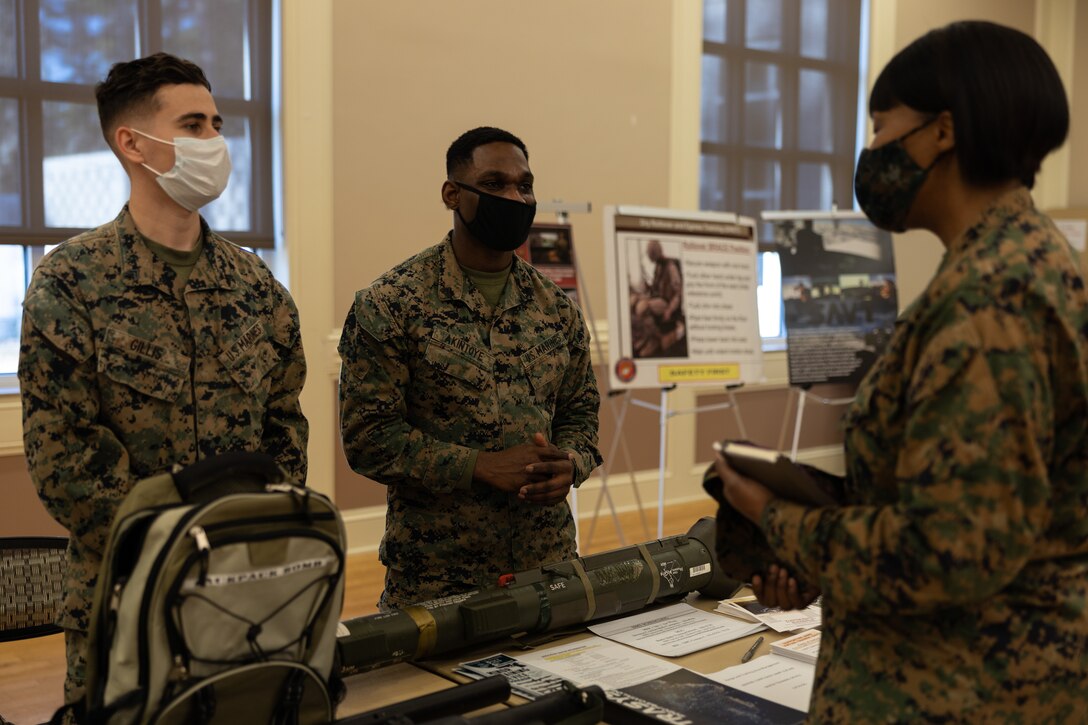 U.S Marine Corps Cpl. Richard Gillis, left, and Cpl. Olorunfemi Akintoye, both assistant trainers at the Simulation Center on Marine Corps Base Camp Lejeune, speak with Lt. Col. NaTasha Everly, commanding officer of Weapons Training Battalion, Stone Bay, MCB Camp Lejeune during the Warfighter Training Symposium at Marston Pavilion on MCB Camp Lejeune, North Carolina, Feb. 28, 2022.