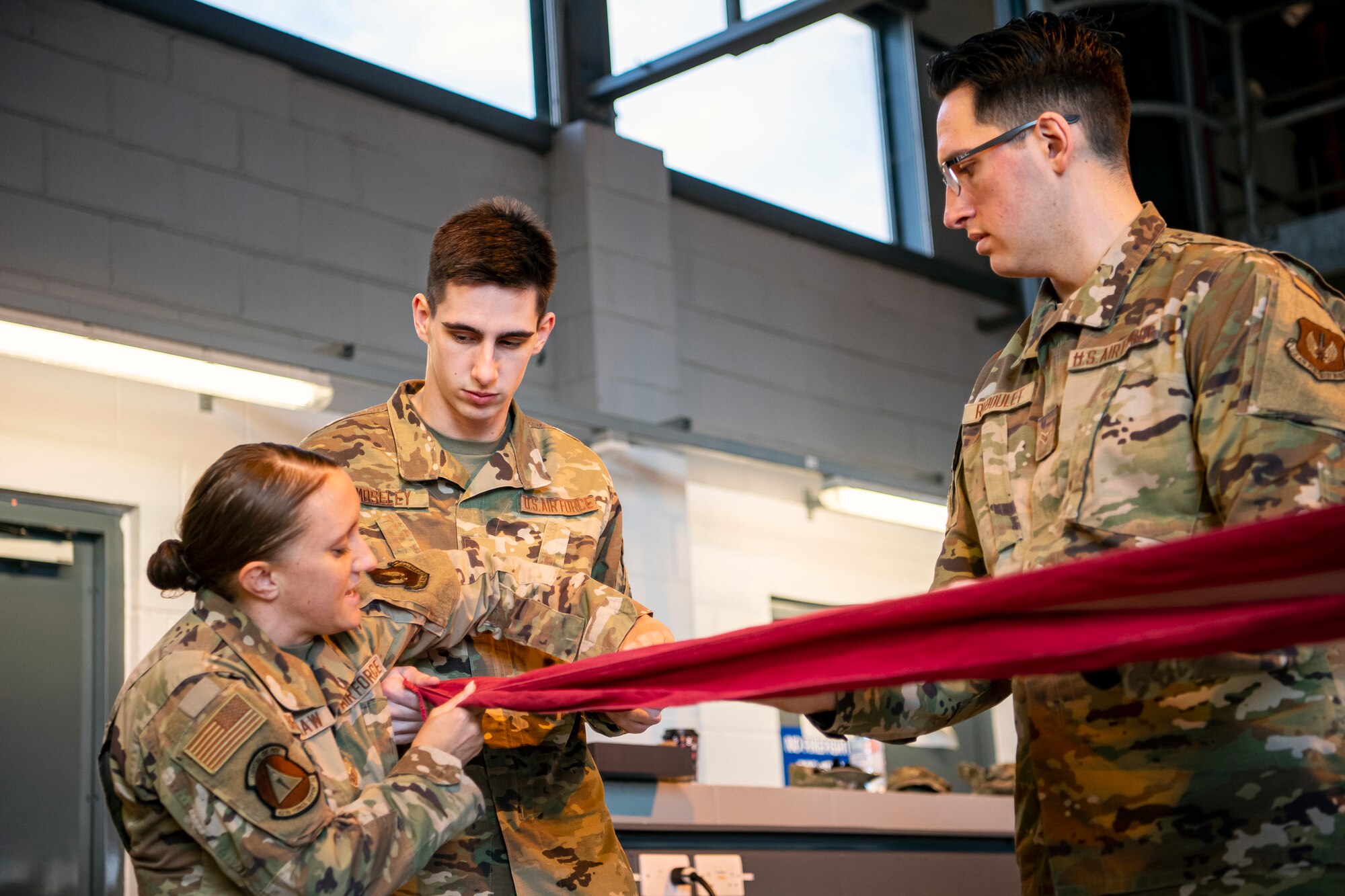 U.S. Air Force Staff Sgt. Haley Bradshaw, left,  423rd Air Base Group honor guard NCO in charge, provides instruction on flag folding at RAF Alconbury, England, Feb. 9, 2022. Airmen from the 423 Air Base Group honor guard conduct weekly training sessions to hone their skills and build chemistry in executing details with Airmen from different squadrons. (U.S. Air Force photo by Senior Airman Eugene Oliver)