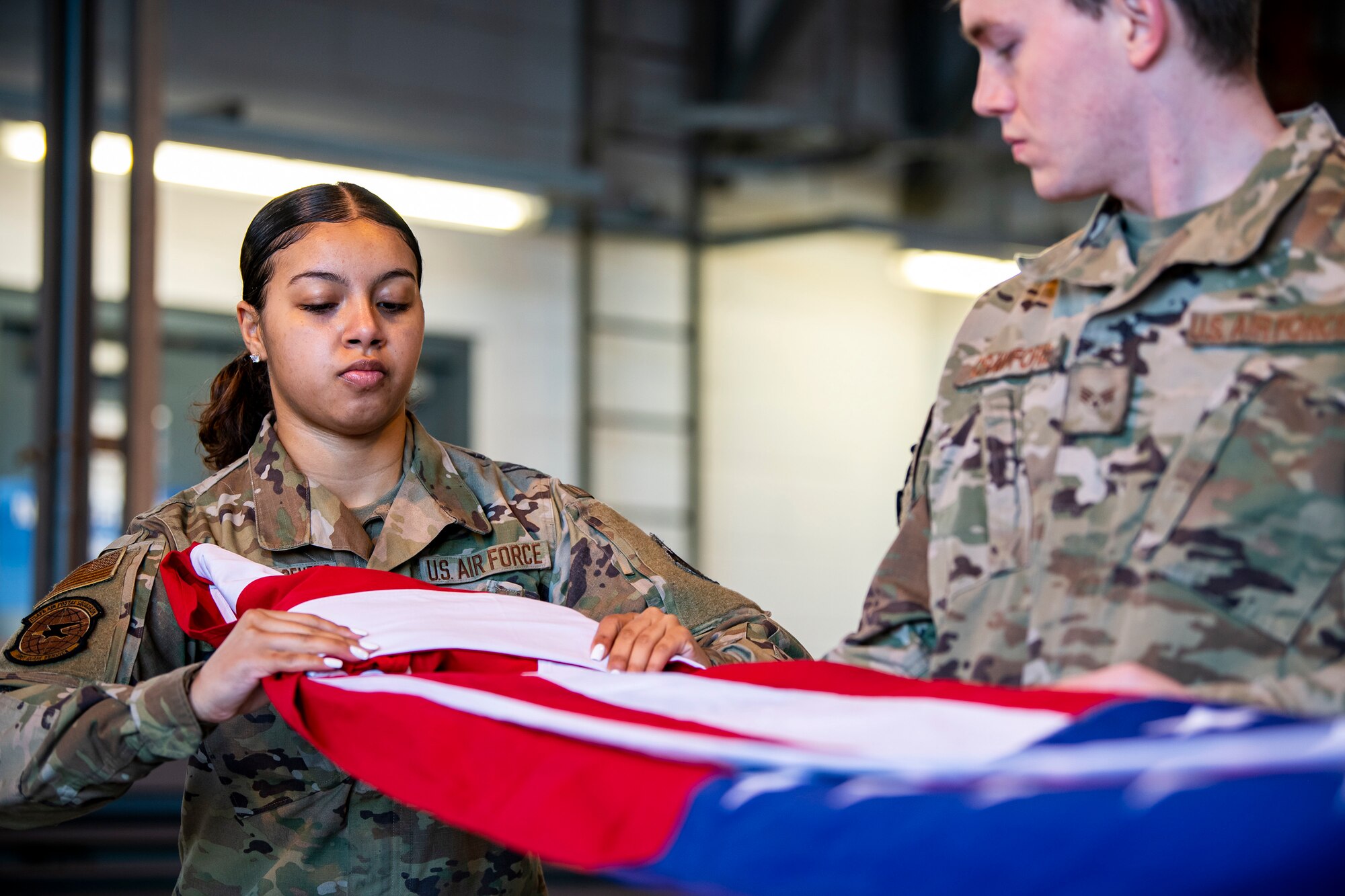 U.S. Air Force Airman 1st Class Jenesi Santos Acevedo, U.S. Air Forces in Europe and Air Forces Africa Air Postal Squadron, Detachment Five mail processing specialist, folds a flag at RAF Alconbury, England, Feb. 9, 2022. Airmen from the 423rd Air Base Group honor guard conduct weekly training sessions to hone their skills and build chemistry in executing details with Airmen from different squadrons. (U.S. Air Force photo by Senior Airman Eugene Oliver)