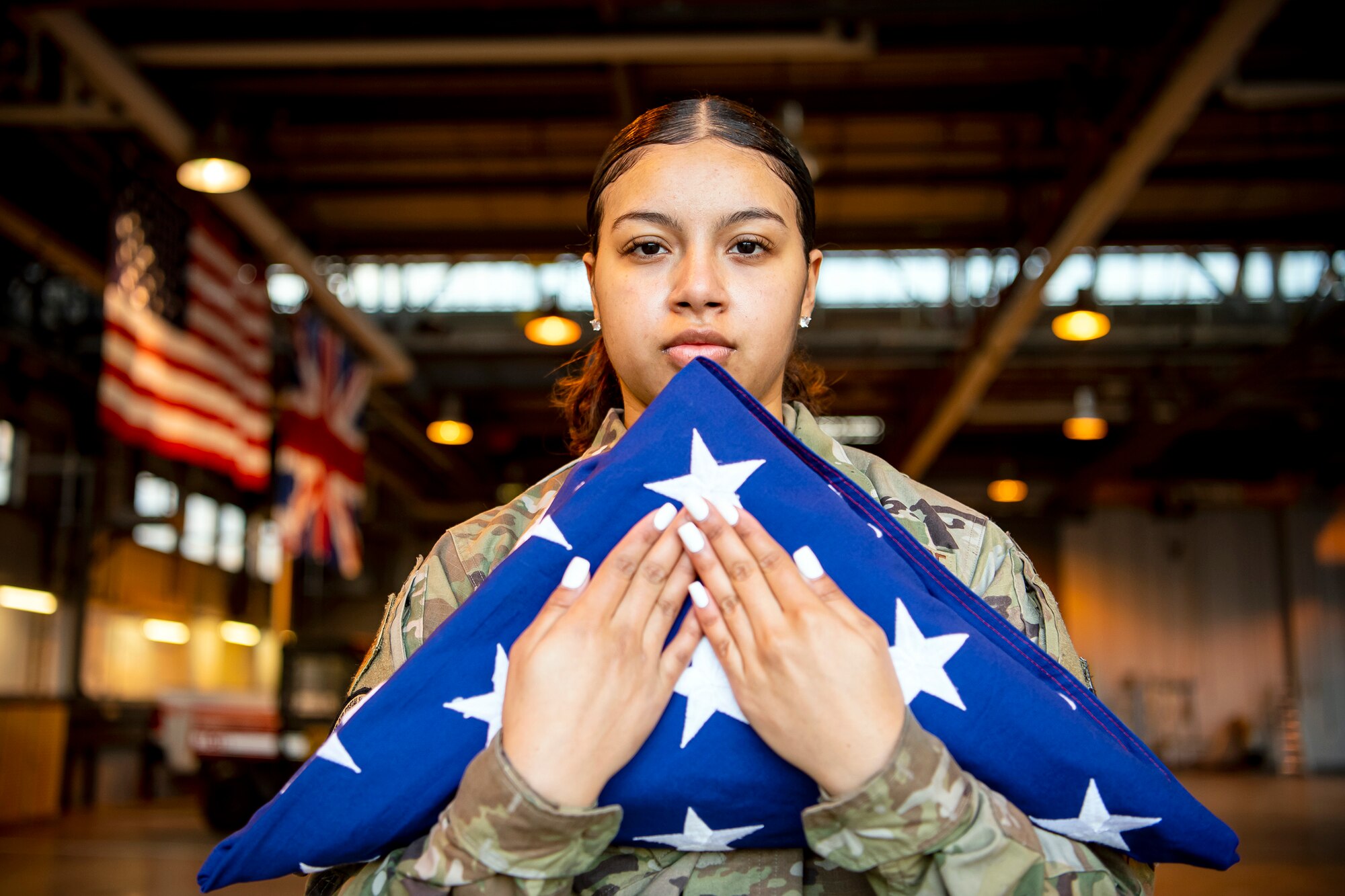 U.S. Air Force Airman 1st Class Jenesi Santos Acevedo, U.S. Air Forces in Europe and Air Forces Africa Air Postal Squadron, Detachment Five mail processing specialist, holds a folded flag at RAF Alconbury, England, Feb. 9, 2022. Airmen from the 423 Air Base Group honor guard conduct weekly training sessions to hone their skills and build chemistry in executing details with Airmen from different squadrons. (U.S. Air Force photo by Senior Airman Eugene Oliver)