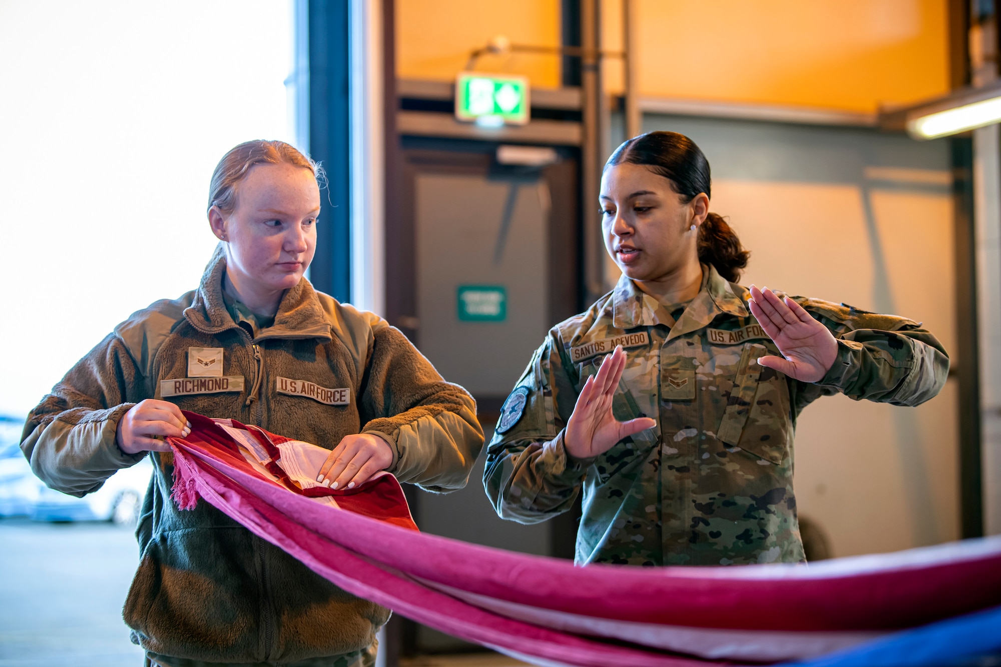 U.S. Air Force Airman 1st Class Jenesi Santos Acevedo, U.S. Air Forces in Europe and Air Forces Africa Air Postal Squadron, Detachment Five mail processing specialist, gives instruction to Airman 1st Class Alyssa Richmond, 423rd Communications Squadron cyber surety apprentice at RAF Alconbury, England, Feb. 9, 2022. Airmen from the 423 Air Base Group honor guard conduct weekly training sessions to hone their skills and build chemistry in executing details with Airmen from different squadrons. (U.S. Air Force photo by Senior Airman Eugene Oliver)