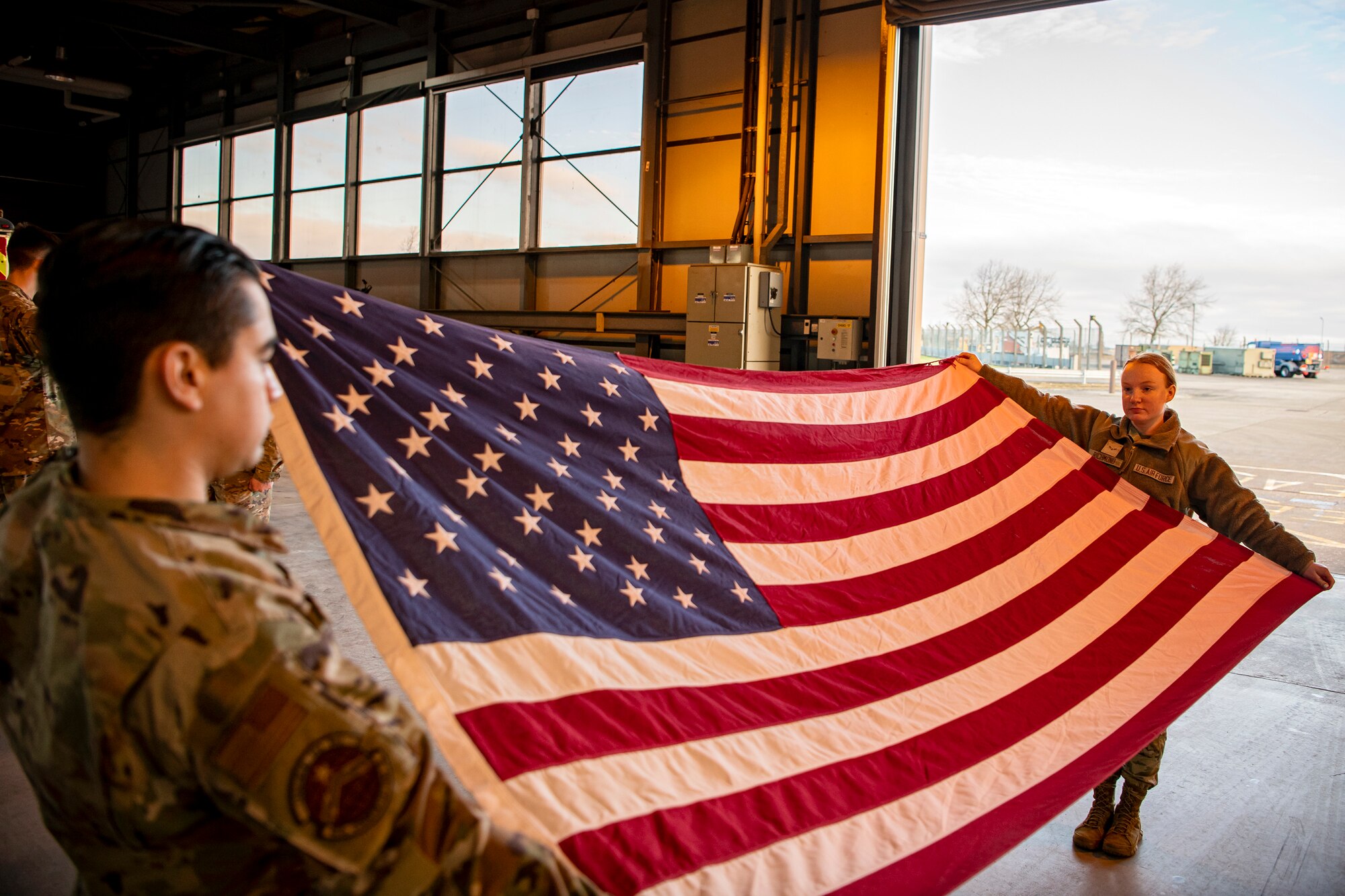 U.S. Air Force Airman Francisco Ruiz, left, 423rd Communications Squadron client systems apprentice and Airman 1st Class Alyssa Richmond, 423rd Communications Squadron cyber surety apprentice, hold a flag at table top position at RAF Alconbury, England, Feb. 9, 2022. Airmen from the 423 Air Base Group honor guard conduct weekly training sessions to hone their skills and build chemistry in executing details with Airmen from different squadrons. (U.S. Air Force photo by Senior Airman Eugene Oliver)