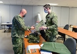 FORT WORTH, Texas (Feb. 16, 2022) - Navy Reserve Region Readiness and Mobilization Command Fort Worth Adaptive Mobilization department staff member Logistics Specialist 1st Class Wilfred Graf, left, issues uniform items to Hospital Corpsman 3rd Class Garrett Beaudry, assigned to Naval Branch Health Clinic San Diego, in preparation for Beaudry’s individual augmentee (IA) assignment to Guantamo Bay, Cuba. IA and mobilization for Selected Reserve processing for Beaudry and other Sailors took place during an adaptive mobilization-enabling event at Navy Reserve Region Readiness and Mobilization Command Fort Worth (REDCOM FW) February 14-18. The event was observed by assessors from Expeditionary Combat Readiness Center, who certified REDCOM FW as a Navy mobilization processing site with delegated Local Area Coordinator for Mobilization (LACMOB) authority. (U.S. Navy photo by Mass Communication Specialist 1st Class Lawrence Davis)