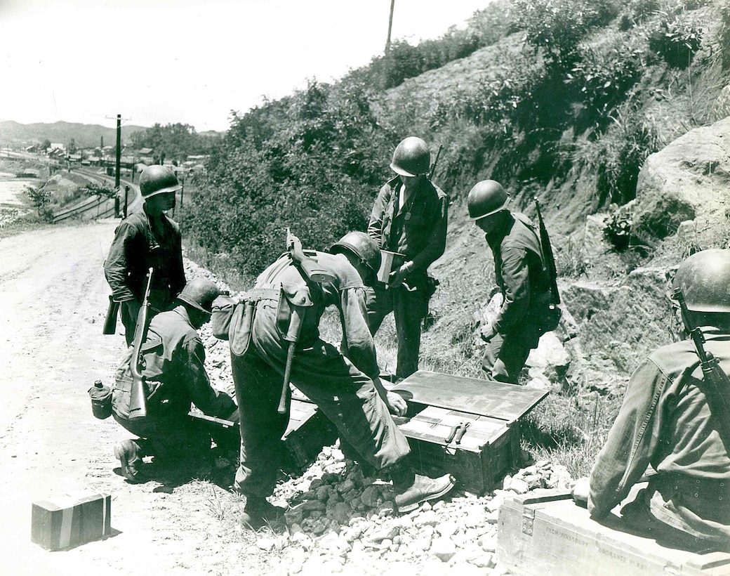 Six men work to take items out of boxes on the side of a road.