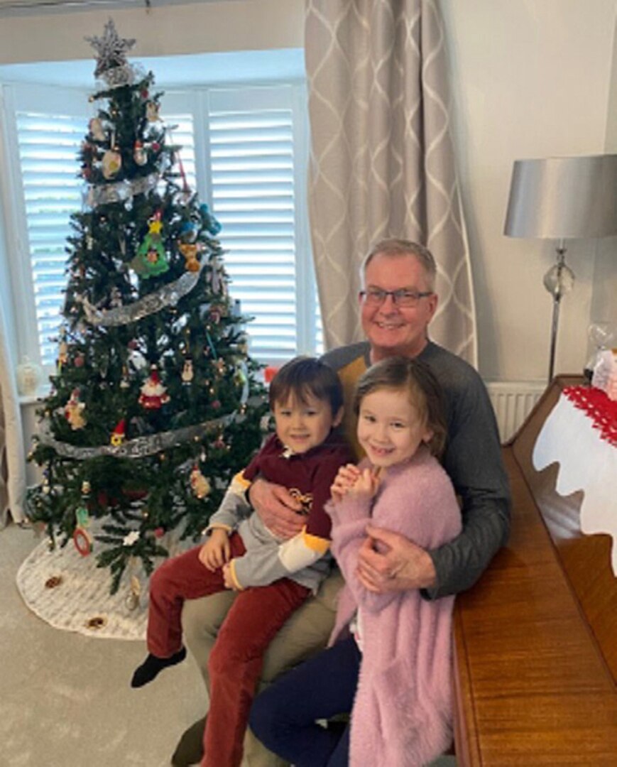 A man and children in front of a Christmas tree.