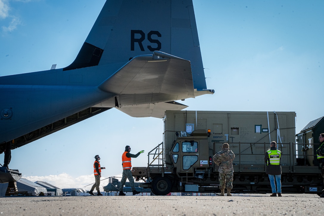 Service members unload cargo from an aircraft.