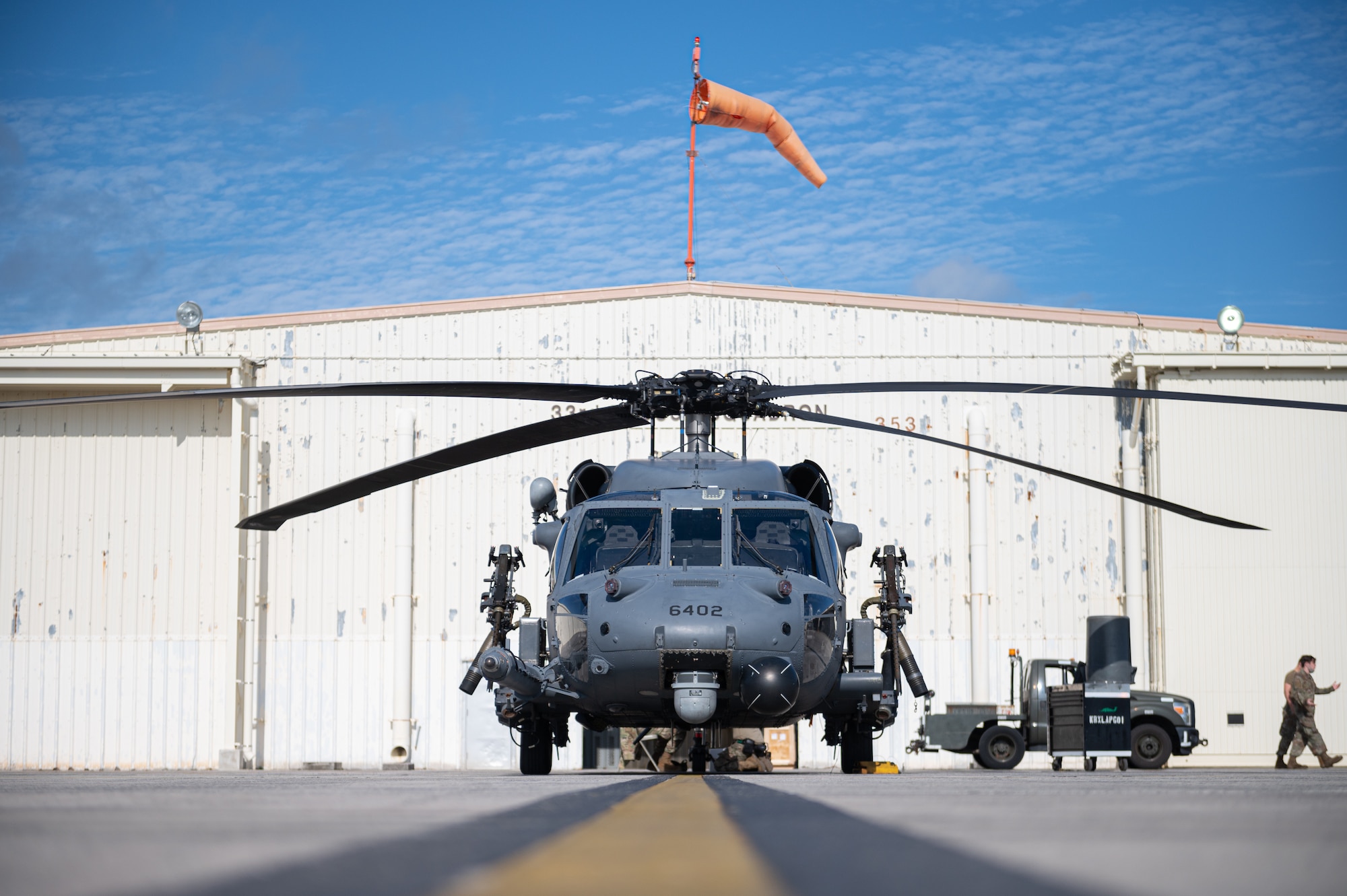 A helicopter parked outside of a hanger