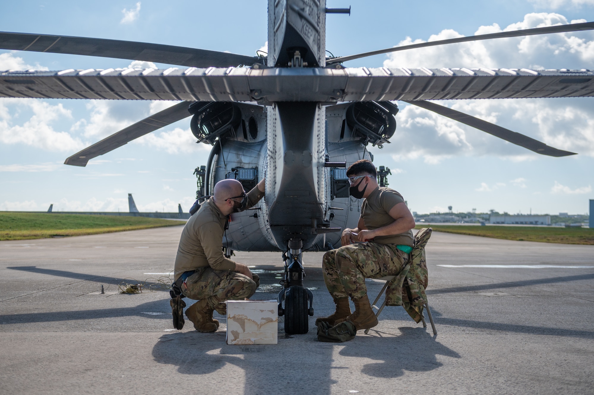 Two Airmen performing maintenance on a helicopter