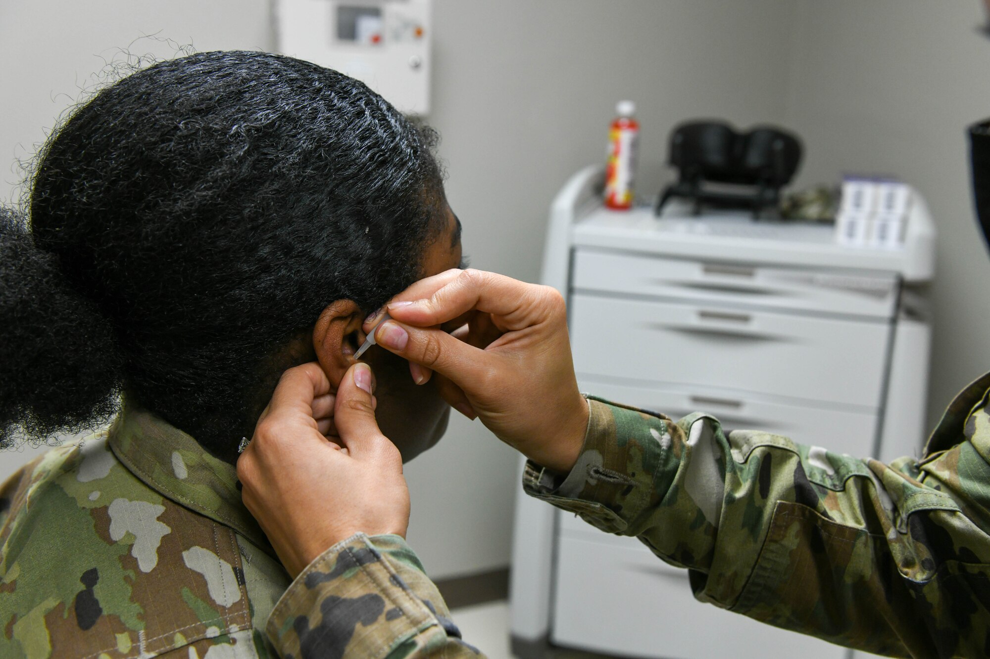 Dr. Jessica Gamboa, 97th Medical Group chief of medical staff, performs battlefield acupuncture on Senior Airman Alexzandria Body, 97th Operational Medical Readiness Squadron pediatric and family health front desk clerk, at Altus Air Force Base, Oklahoma, Feb. 10, 2022. Gamboa and Dr. Nicholas Martin, 97th Operational Medical Readiness Squadron family medicine physician, perform battlefield acupuncture on Airmen of the 97th Air Mobility Wing and their families. (U.S. Air Force photo by Airman 1st Class Trenton Jancze)