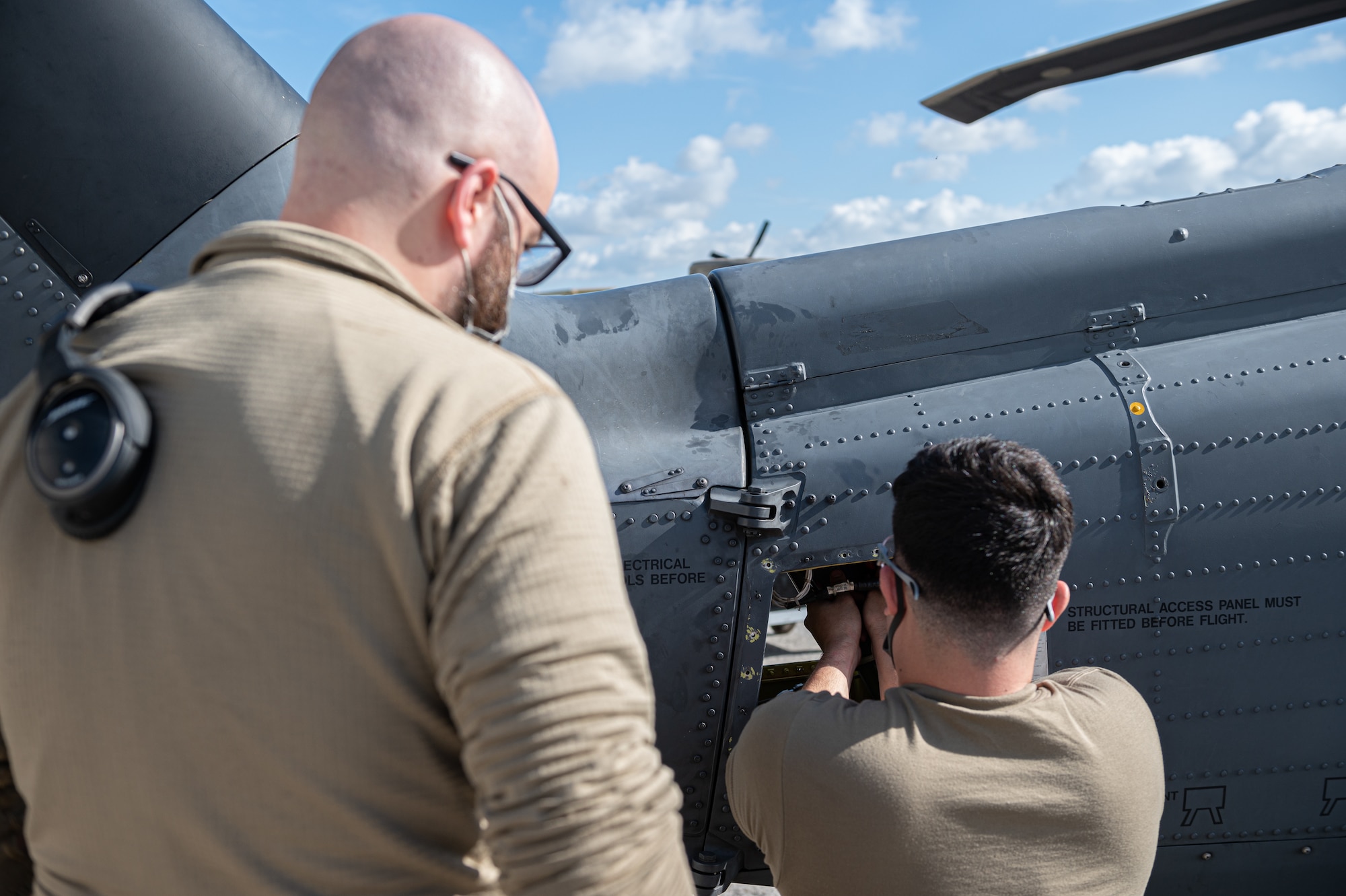 Two Airman performing maintenance on a helicopter