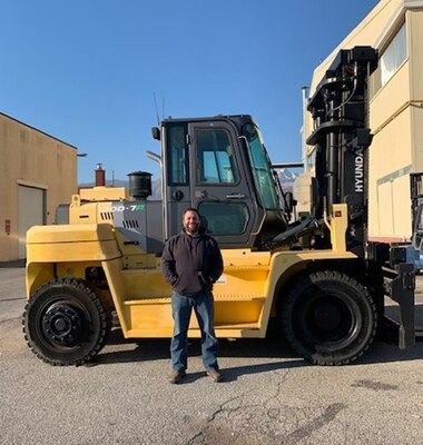 A man poses in front of material handling equipment.