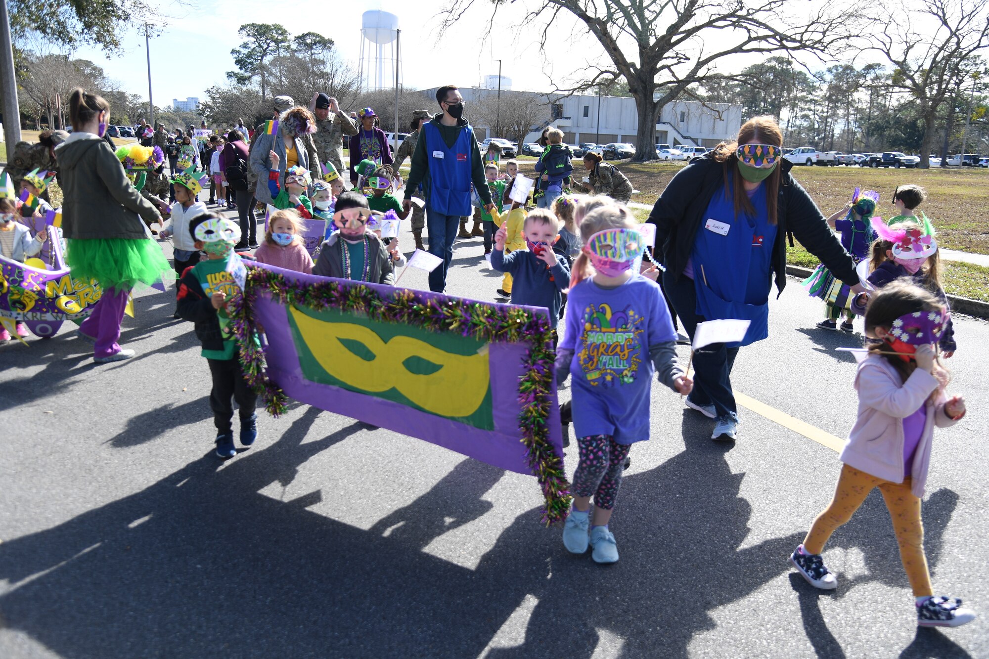 The Keesler Child Development Center celebrates Mardi Gras with a parade at Keesler Air Force Base, Mississippi, March 1, 2022. Family members line the street to watch their children parade by them while wearing festive clothing, beads and make-shift floats. (U.S. Air Force photo by Kemberly Groue)