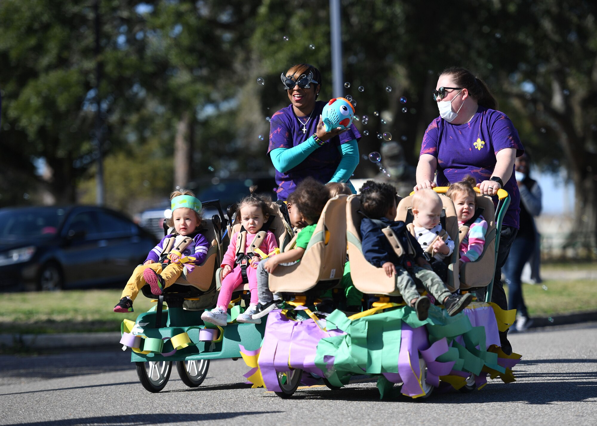 The Keesler Child Development Center celebrates Mardi Gras with a parade at Keesler Air Force Base, Mississippi, March 1, 2022. Family members line the street to watch their children parade by them while wearing festive clothing, beads and make-shift floats. (U.S. Air Force photo by Kemberly Groue)