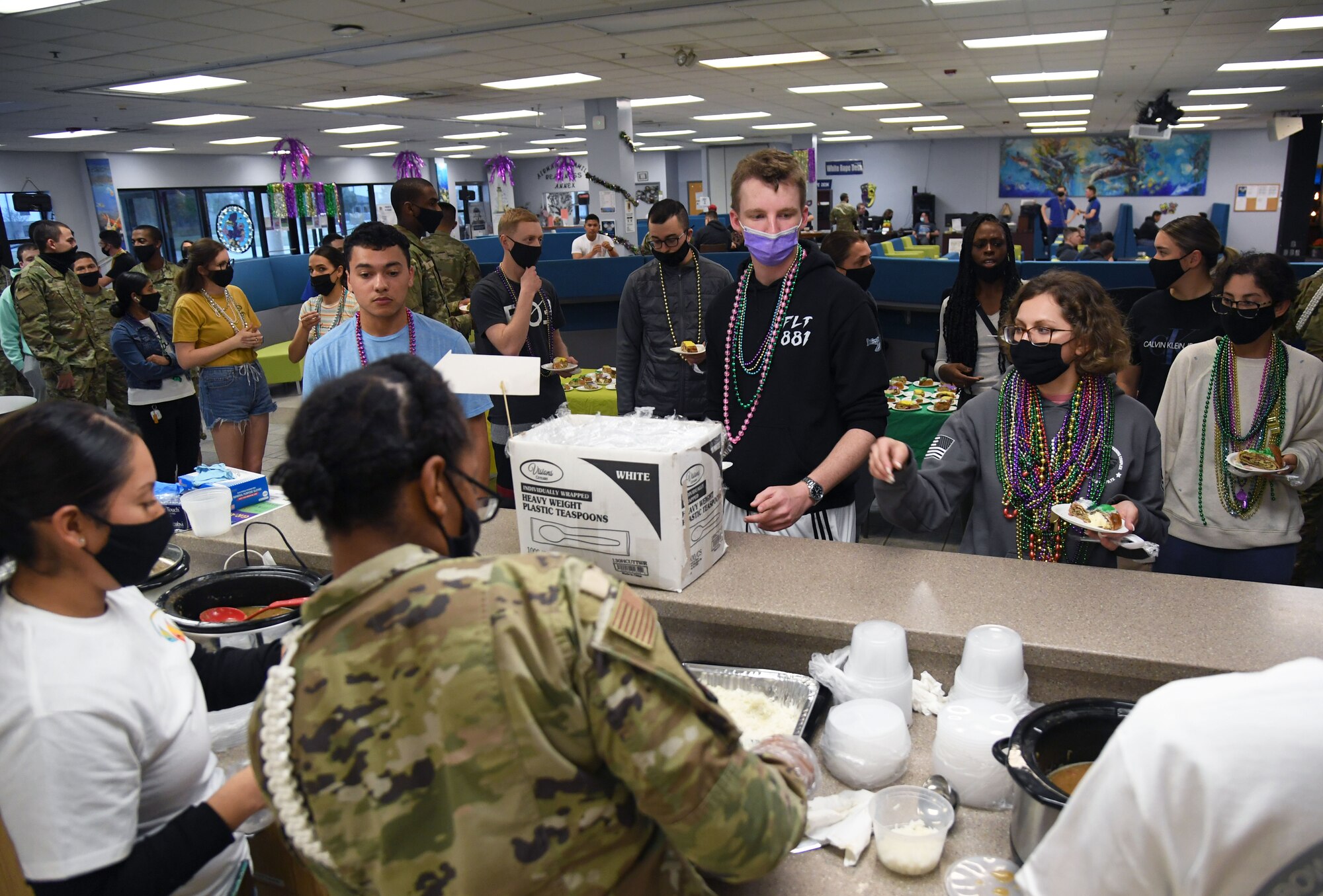 Airmen from the 81st Training Group stand in line for gumbo samples inside the Levitow Training Support Facility at Keesler Air Force Base, Mississippi, March 1, 2022. The event, hosted by the 81st Training Wing chaplains office, was in celebration of Mardi Gras and also provided slices of king cake. (U.S. Air Force photo by Kemberly Groue)