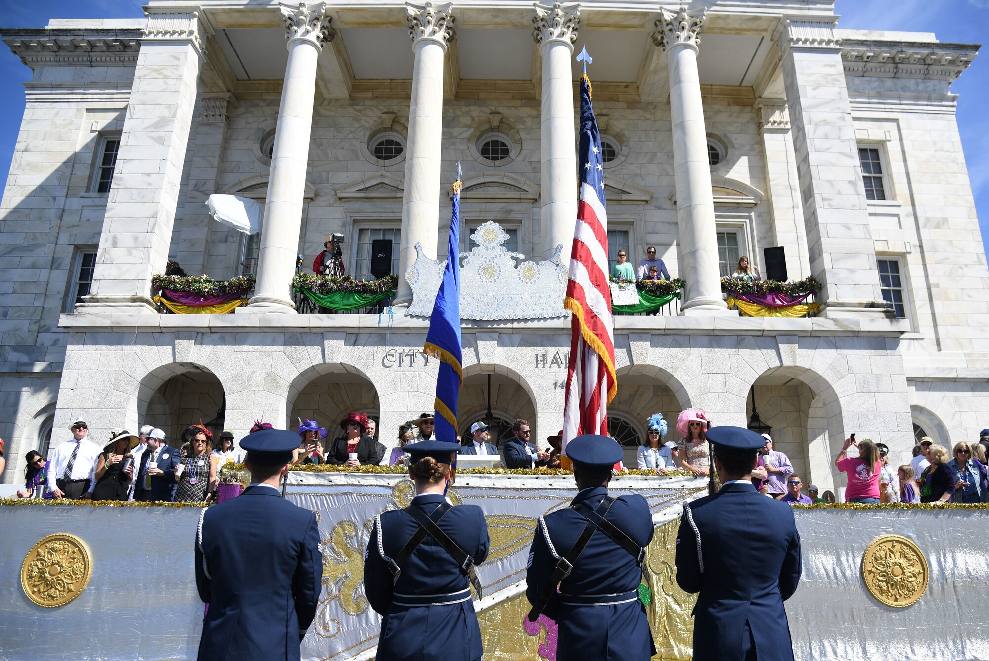 Members of the Keesler Air Force Base Honor Guard present the colors in front of City Hall during the Gulf Coast Carnival Association Mardi Gras parade in Biloxi, Mississippi, March 1, 2022. Keesler personnel participate in local parades every Mardi Gras season to show their support of the communities surrounding the installation. (U.S. Air Force photo by Kemberly Groue)
