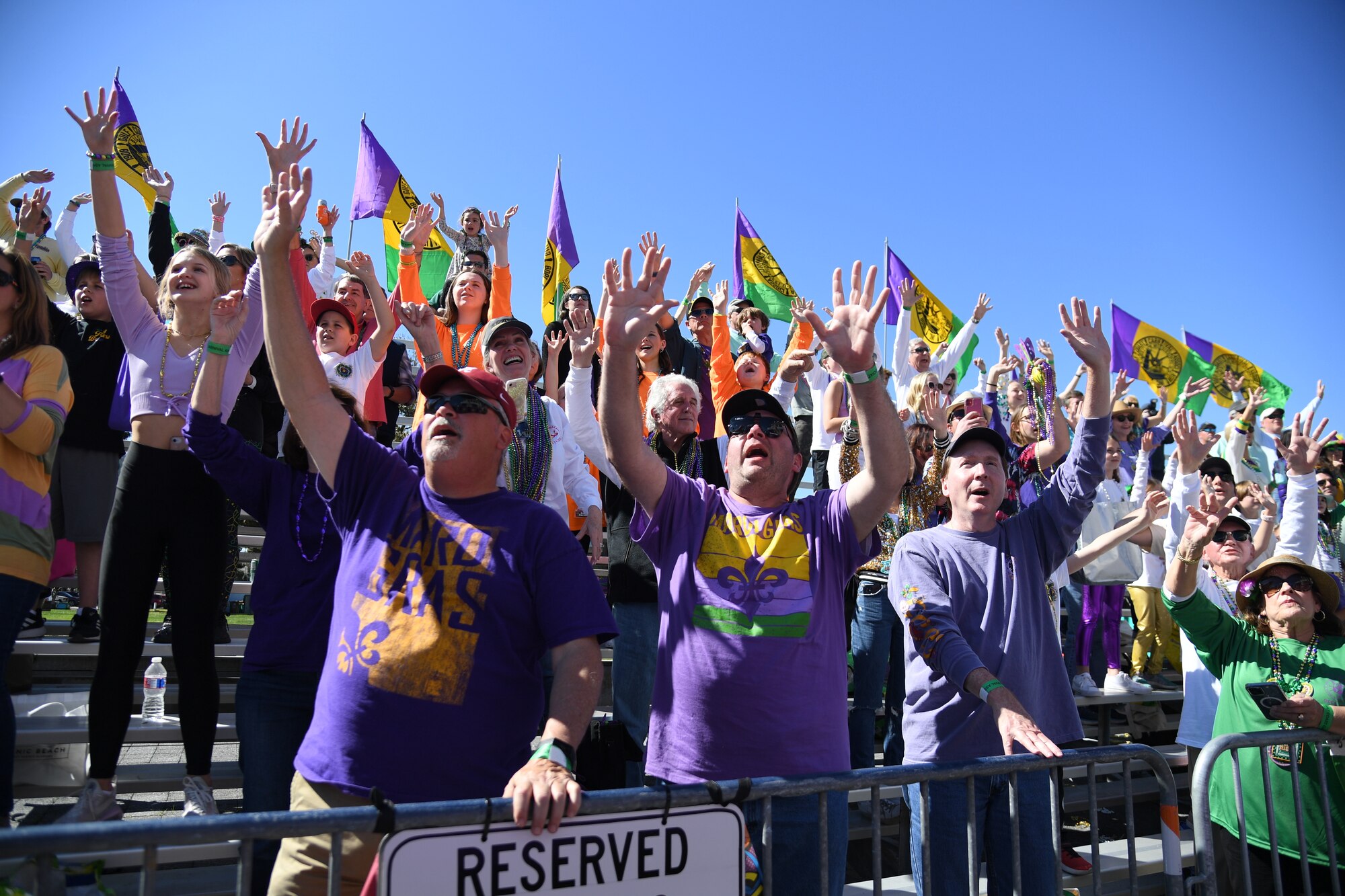 Parade attendees raise their hands and yell for bead throws from floats during the Gulf Coast Carnival Association Mardi Gras parade in Biloxi, Mississippi, March 1, 2022. Keesler personnel participate in local parades every Mardi Gras season to show their support of the communities surrounding the installation. (U.S. Air Force photo by Kemberly Groue)