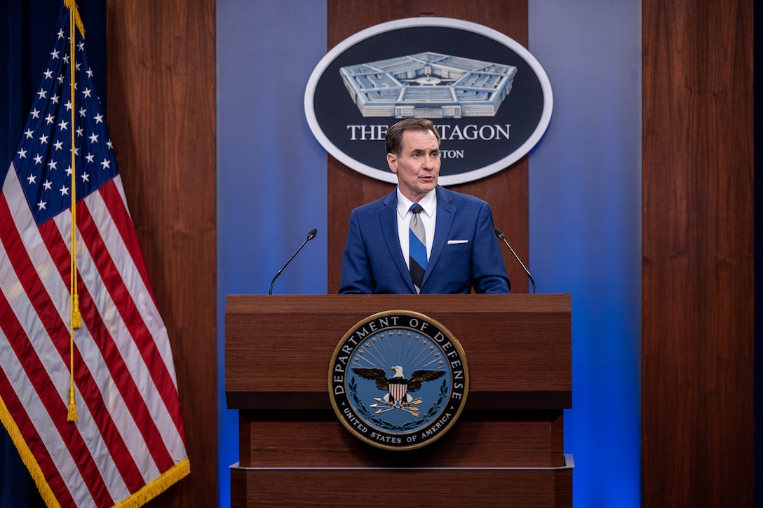 Civilian speaks at a lectern with DOD seal on it.