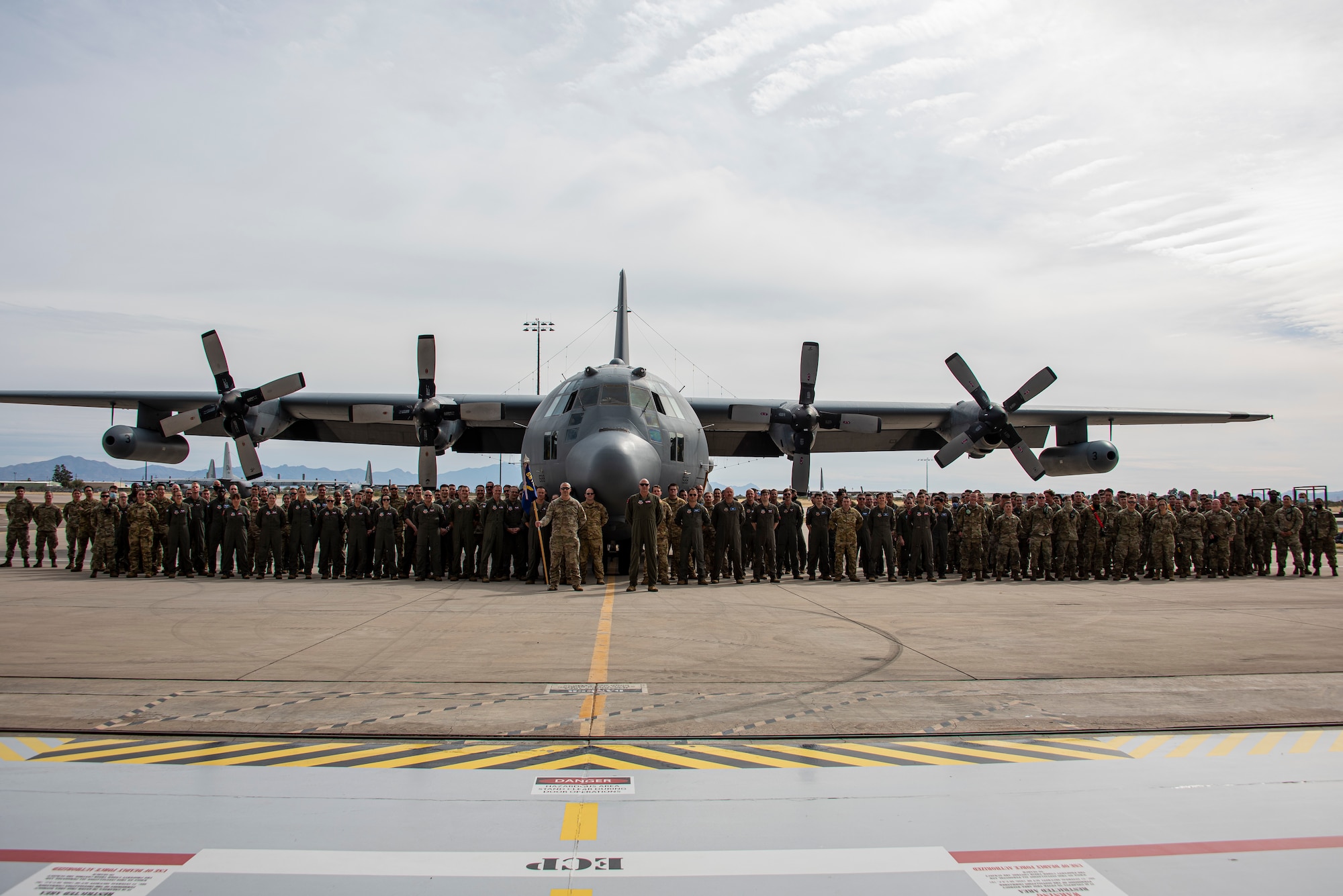 A group of people pose for a photo in front of an aircraft.