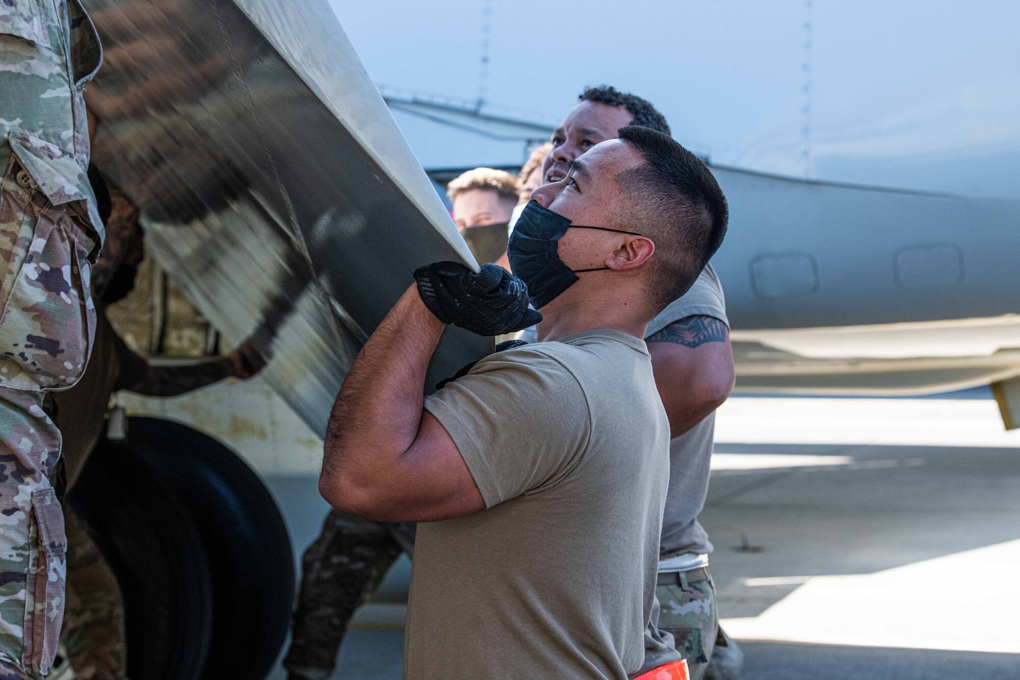 An Airman holds the weight of an aircraft wing flap.