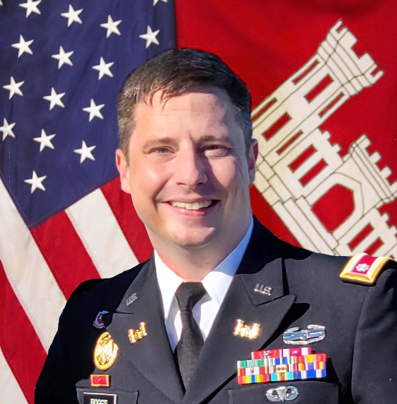 white man in blue uniform in front of flags