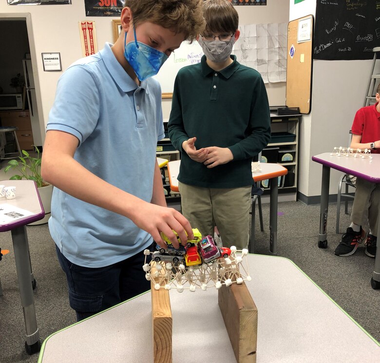 A student stacks toy cars on his bridge to test its strength during a hands-on learning experience with the U.S. Army Corps of Engineers – Alaska District on Feb. 23 at Pacific Northern Academy in Anchorage.