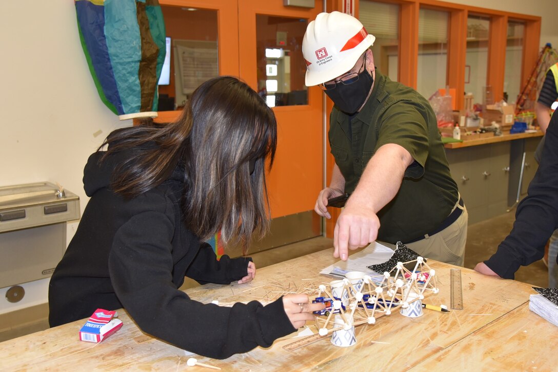Nathan Epps, acting deputy chief for the Engineering, Construction and Operations Division, stresses the importance of triangles while testing the load capacity of a student’s bridge design with a toy car on Feb. 22 at Clark Middle School in Anchorage.
