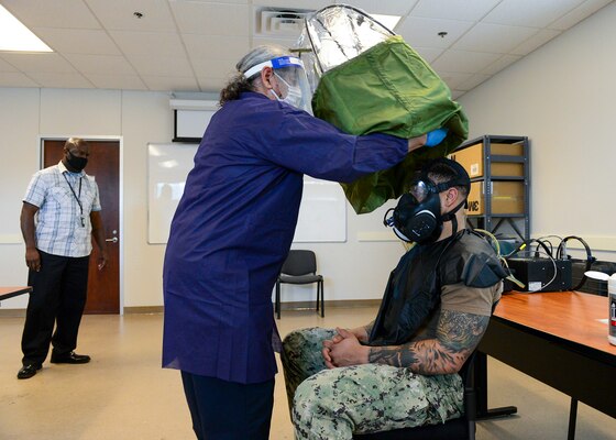 FORT WORTH, Texas (Feb. 16, 2022) - Joint Service Mask Leakage Tester Arnie Perez, center, performs a fit test of the M-50 gas mask for Navy Reserve Yeoman 1st Class Andre Polk, assigned to Navy Reserve Center New York City, at Navy Reserve Region Readiness and Mobilization Command Fort Worth (REDCOM FW), in preparation for Polk’s scheduled mobilization to Qatar. Selected Reserve mobilization processing for Polk and other Sailors took place during an adaptive mobilization-enabling event at REDCOM FW February 14-18. The event was observed by assessors from Expeditionary Combat Readiness Center, who certified REDCOM FW as a Navy mobilization processing site with delegated Local Area Coordinator for Mobilization (LACMOB) authority. (U.S. Navy photo by Mass Communication Specialist 1st Class Lawrence Davis)
