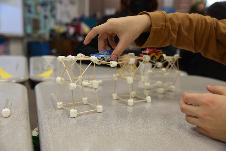 A student tests the load-bearing strength of his bridge by adding a second toy car during a National Engineers Week event with the U.S. Army Corps of Engineers – Alaska District on Feb. 25 at Lake Hood Elementary School in Anchorage.