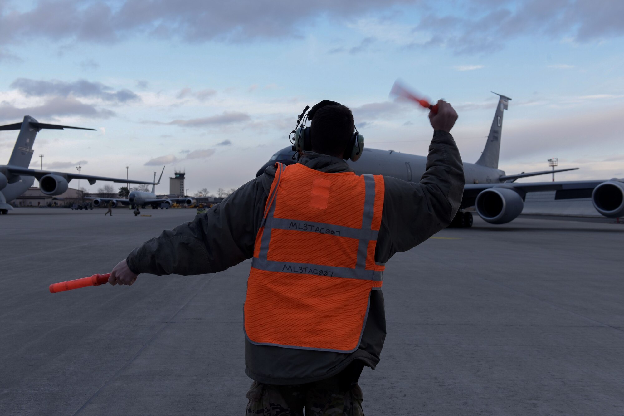 Man guides a plane on the flightline