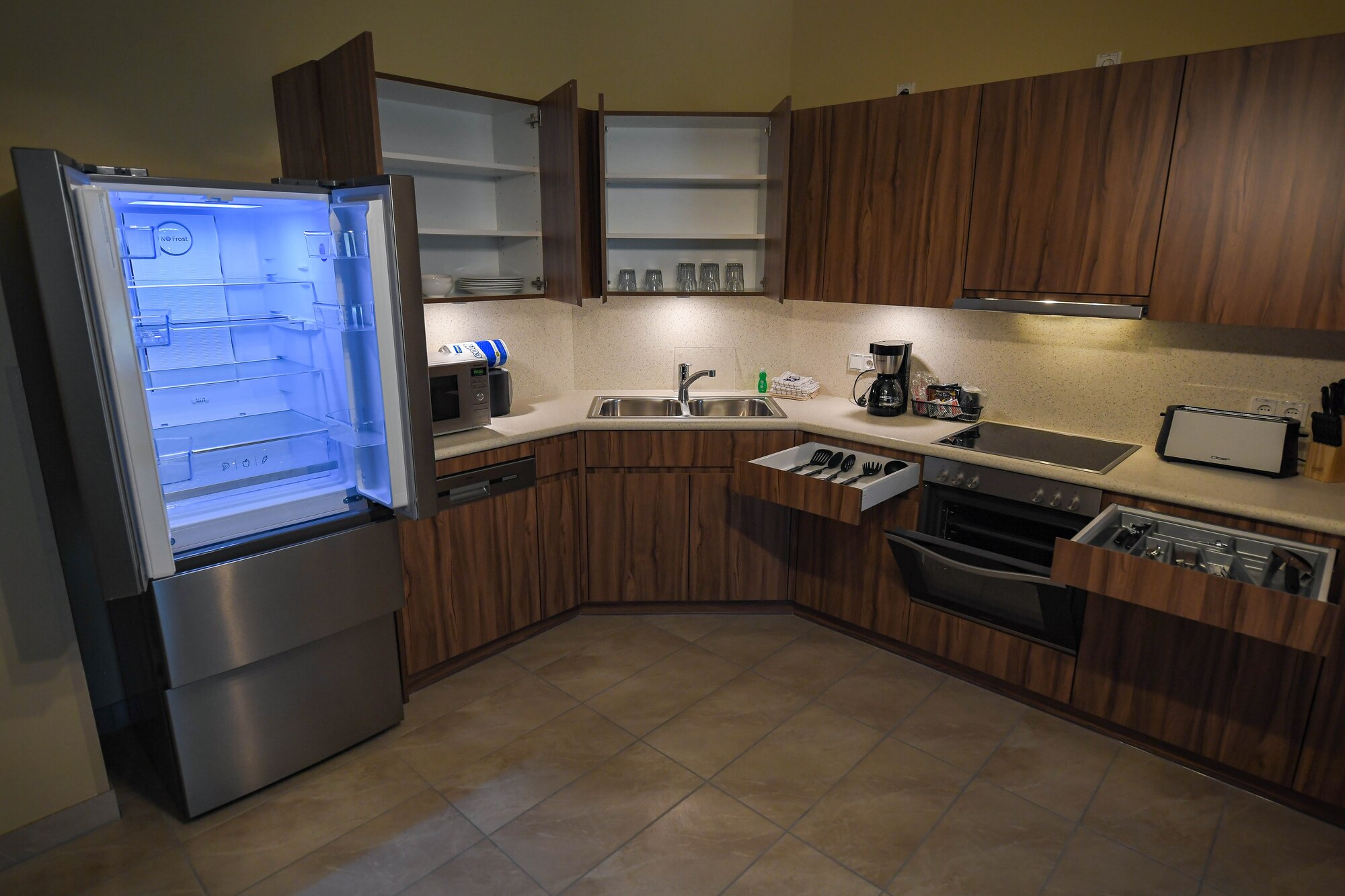 A fully furnished kitchen is ready for use at a new temporary lodging facility at Ramstein Air Base, Germany, Feb. 23, 2022. The TLF offers guests a fully furnished kitchen with a stove, stove top, refrigerator, coffee maker, utensils and dishes. (U.S. Air Force photo by Airman 1st Class Jared Lovett)