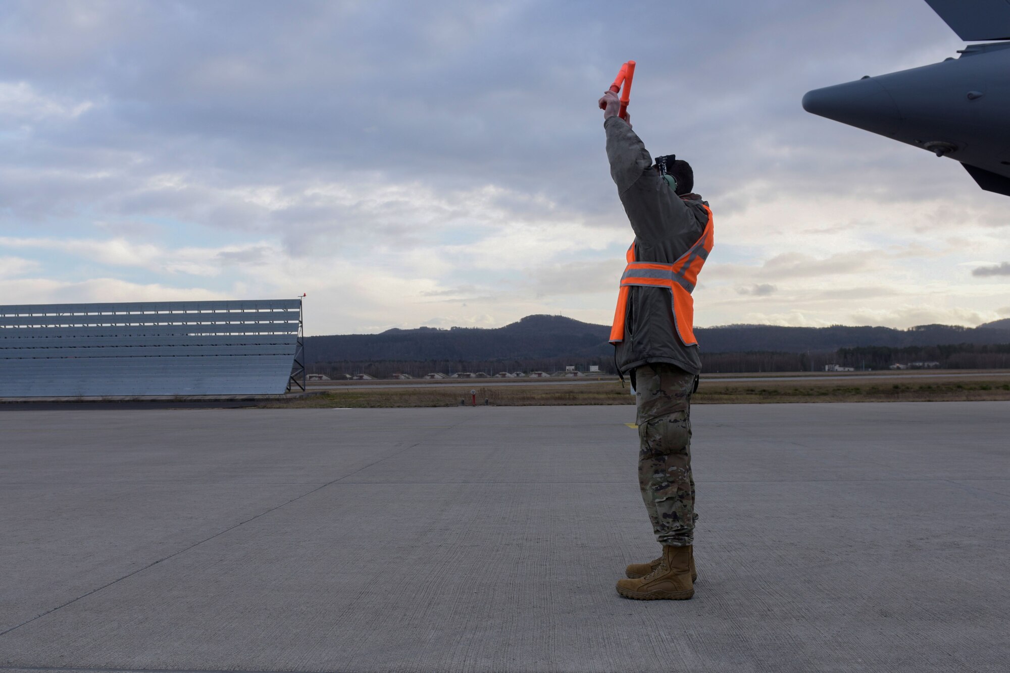 Man guides an aircraft on the flightline