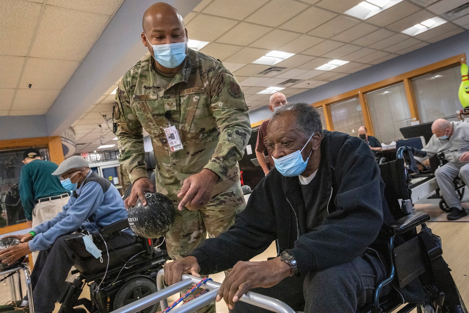 U.S. Air Force Staff Sgt. Edward D. Simms, 204th Intelligence Squadron, 108th Wing, New Jersey Air National Guard, hands a bowling ball to James Dow, a resident at the New Jersey Veterans Memorial Home at Vineland, at the home’s bowling alley in Vineland, New Jersey, Feb. 24, 2022. More than 70 New Jersey National Guard Soldiers and Airmen are serving at the home.