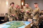 U.S. Army Capt. Nicholas Charnley, Maj. Dermot Gavin, and Maj. Jared Kausner, assigned to the 27th Infantry Brigade Combat Team, New York Army National Guard, discuss the theoretical application of multidomain operations in a modern-day version of the Battle of Saipan in World War II during a leaders workshop in Syracuse, New York, Feb. 26, 2022. The workshop served to prepare the 27th IBCT's senior leaders for upcoming deployments and development of their future forces.