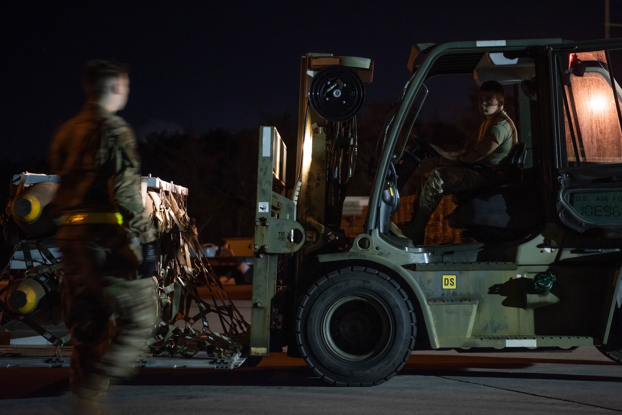 Airmen work to move munitions at night.