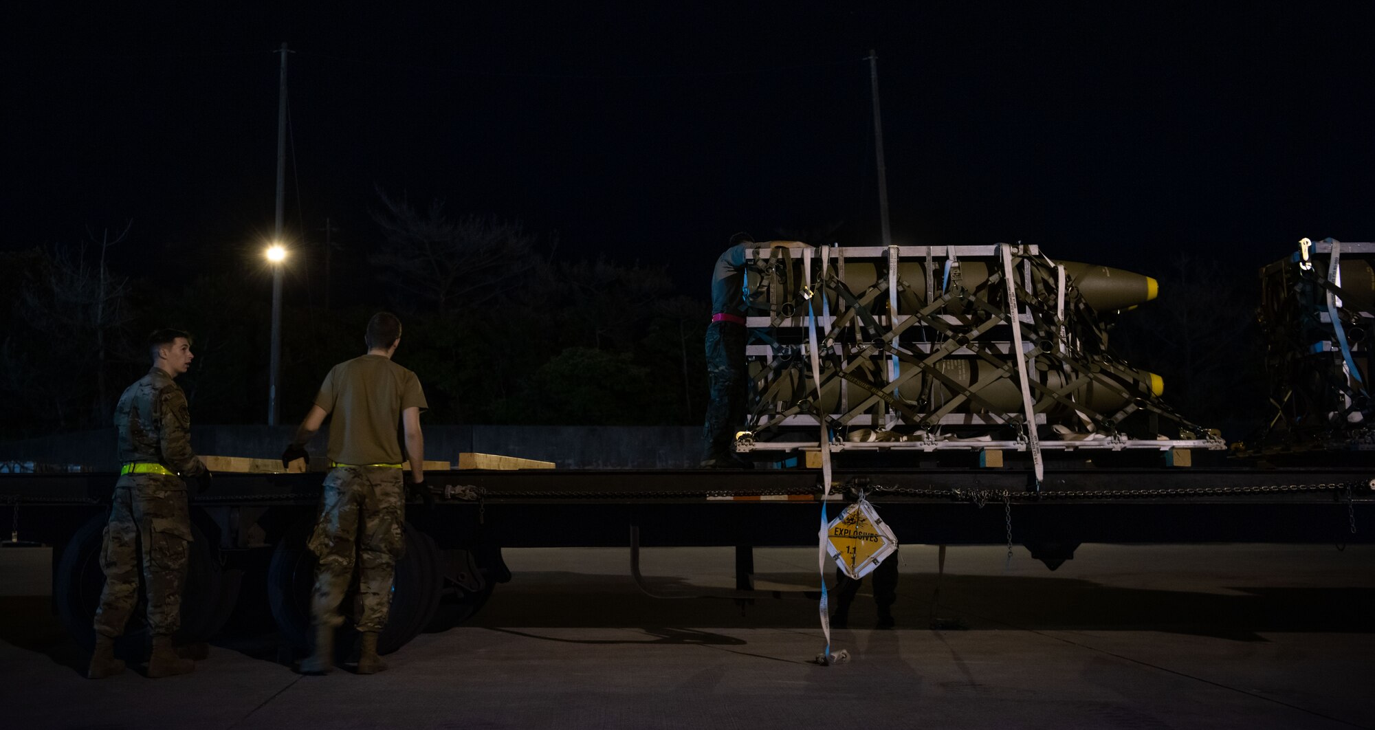 Airmen work to move munitions at night.