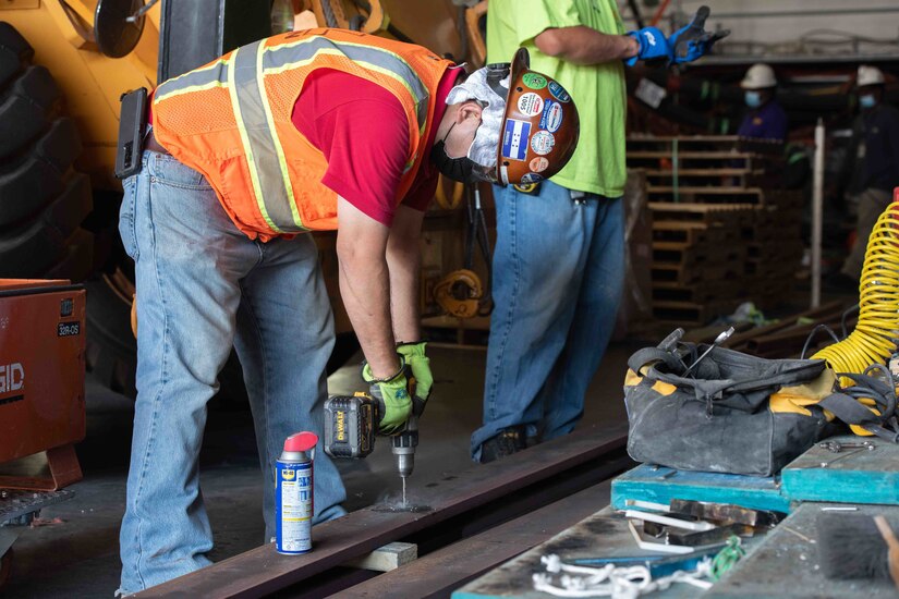 A worker drills steel.