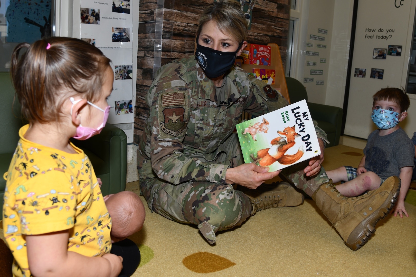 Woman in military uniform reads to a child.