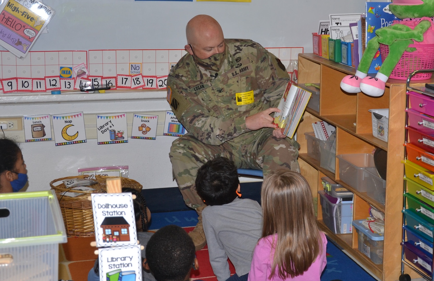 Man in military uniform reads a book to children.