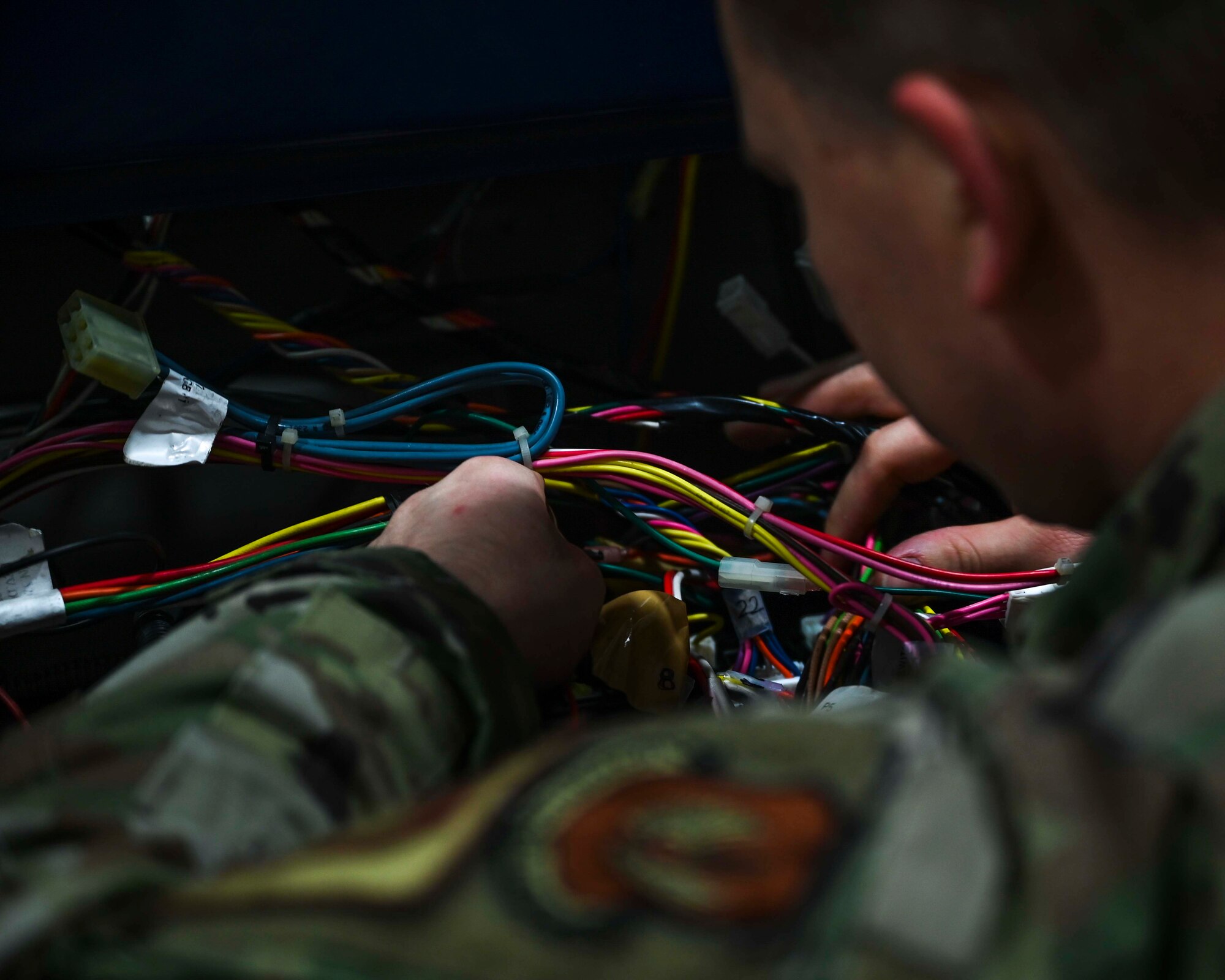 U.S. Air Force Senior Airman Dylan Colt, 100th Logistics Readiness Squadron vehicle maintenance journeyman (right), Airman 1st Class Cameron French, 100th Security Forces response member (left), and Senior Airman Michael Pingitore (middle), base defense operations center controller, discuss a headlight system defect on a security forces patrol vehicle assigned to the 100th LRS, Royal Air Force Mildenhall, England, Feb. 2, 2022. In order to keep patrol vehicles mission-ready, a functioning headlight system is necessary to  challenge a speeding or suspicious driver. (U.S. Air Force photo by Airman 1st Class Viviam Chiu)