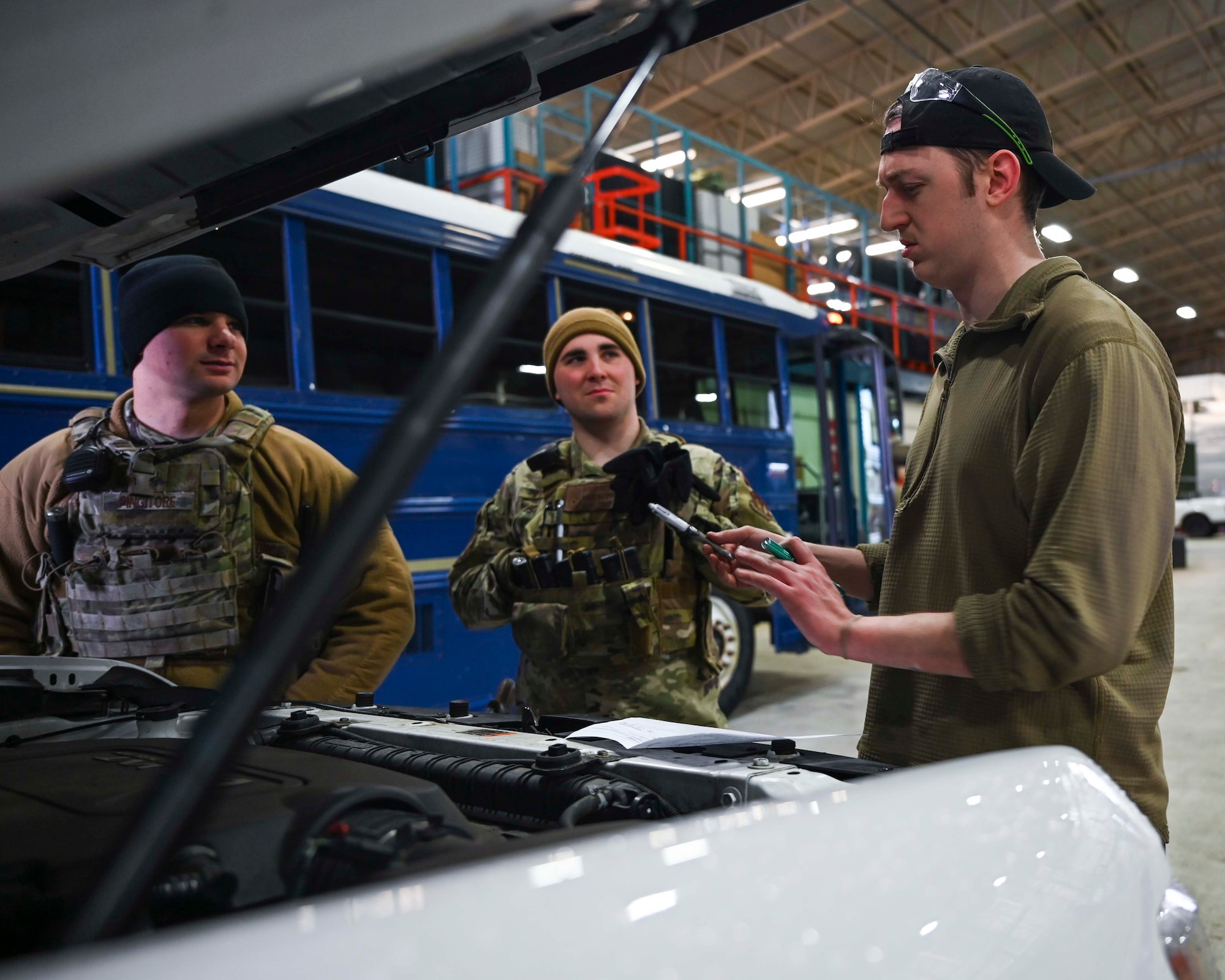 U.S. Air Force Senior Airman Dylan Colt, 100th Logistics Readiness Squadron vehicle maintenance journeyman (right), Airman 1st Class Cameron French, 100th Security Forces response member (left), and Senior Airman Michael Pingitore (middle), base defense operations center controller, discuss a headlight system defect on a security forces patrol vehicle assigned to the 100th LRS, Royal Air Force Mildenhall, England, Feb. 2, 2022. In order to keep patrol vehicles mission-ready, a functioning headlight system is necessary to  challenge a speeding or suspicious driver. (U.S. Air Force photo by Airman 1st Class Viviam Chiu)