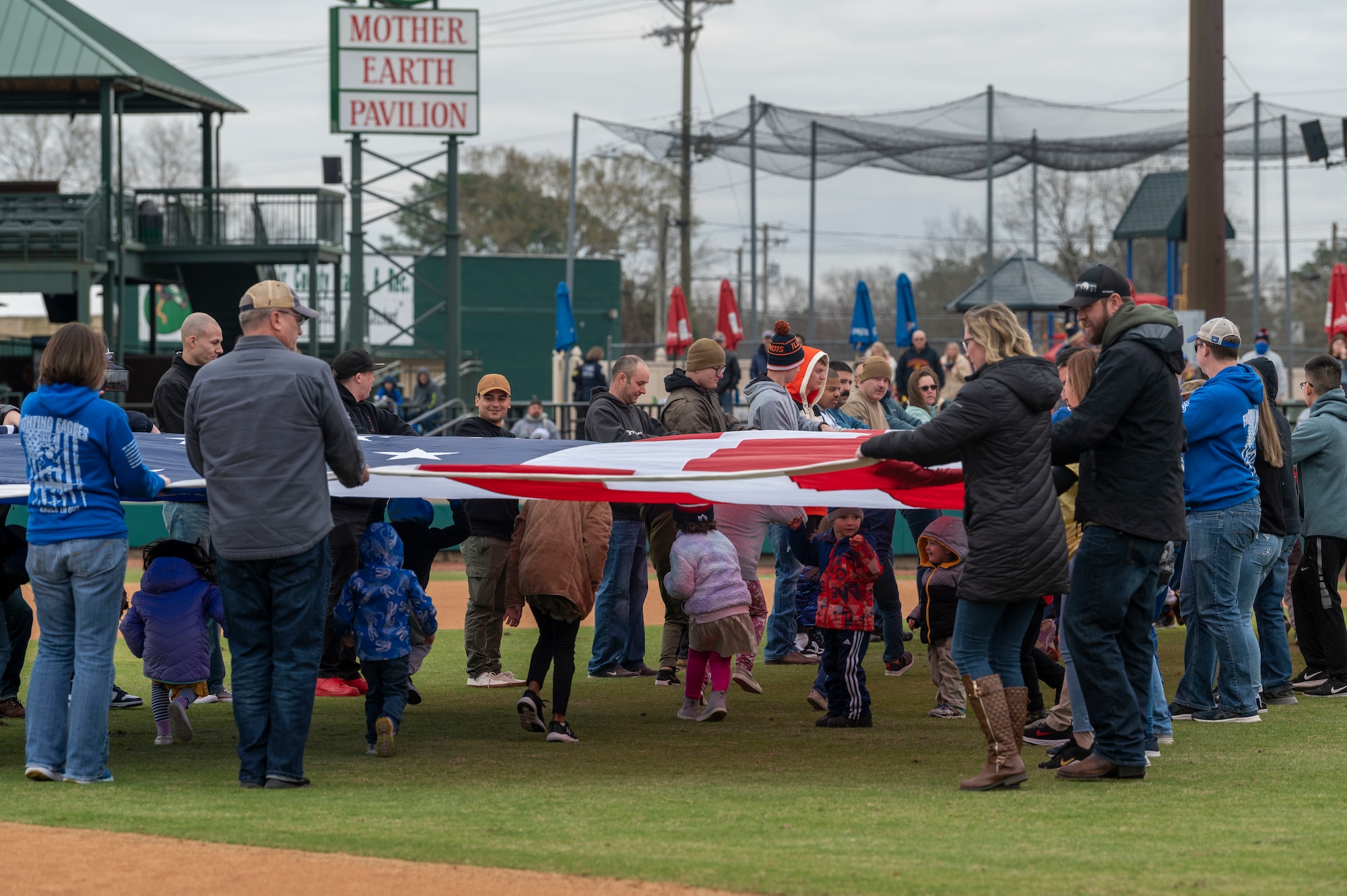 Airmen from Seymour Johnson Air Force Base hold the American Flag during the 12th Annual Freedom Classic baseball series at Grainger Stadium in Kinston, North Carolina, on Feb. 26, 2022. Airmen held the flag during the singing of the National Anthem, which was accompanied by an F-15E Strike Eagle flyover. (U.S. Air Force photo by Airman 1st Class Kevin Holloway)