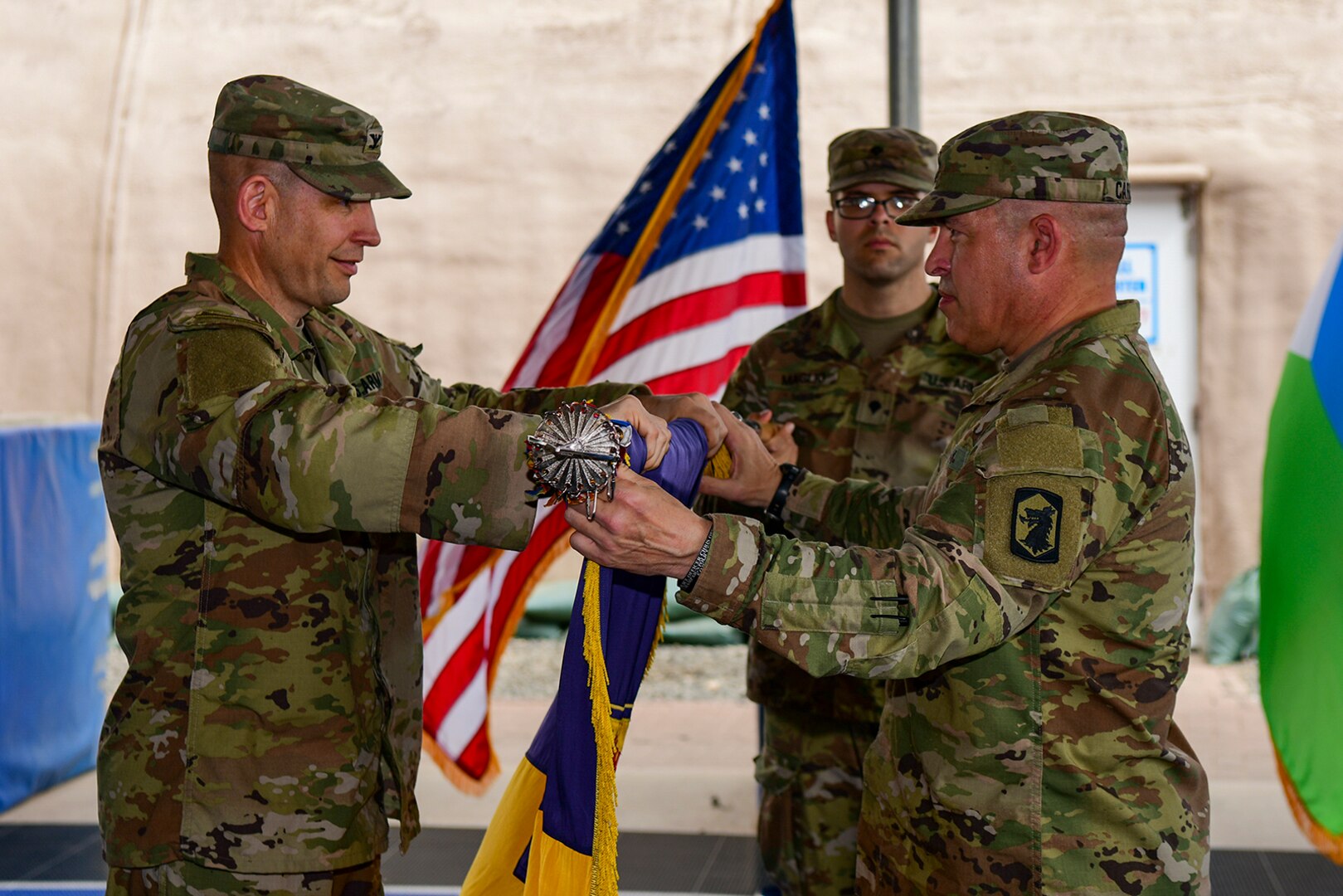 U.S. Army Col. Justin Towell, left, incoming chief of staff of Combined Joint Task Force – Horn of Africa (CJTF-HOA), and U.S. Army Command Sgt. Maj. Richard Carroll, senior enlisted leader of the 404th Maneuver Enhancement Brigade (MEB), assume authority of the CJTF-HOA mission during a transfer of authority ceremony at Camp Lemonnier, Djibouti, Feb. 26, 2022.