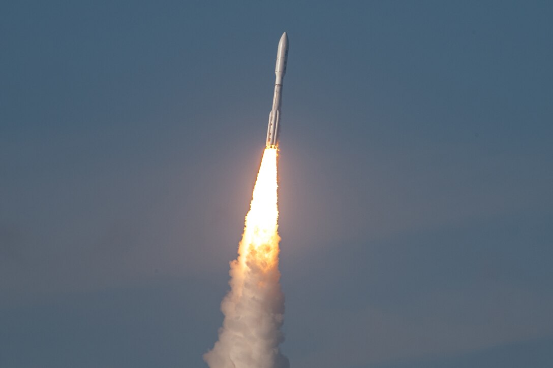 A rocket soars through a dark blue sky.