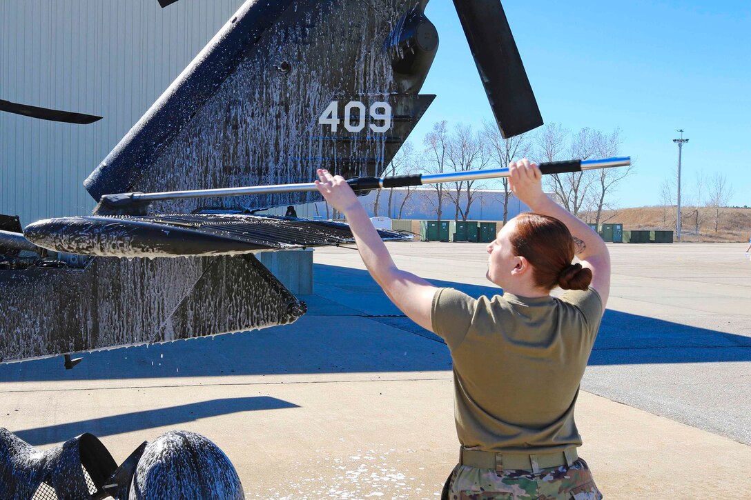 A soldier washes a helicopter.