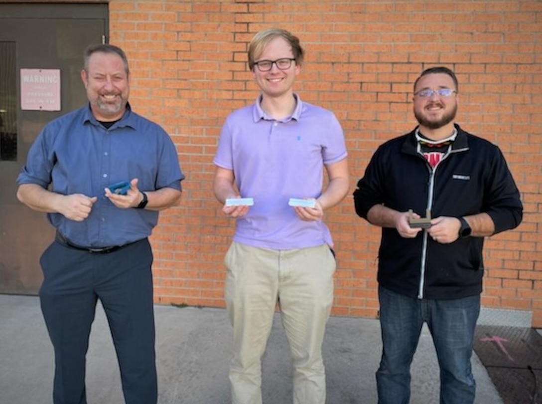 (left to right) Naval Surface Warfare Center Panama City Division (NSWC PCD) Hydrospace Laboratory Manager Dr. Christopher Musto, Hydrospace Laboratory Mechanical Engineer Jake Moody V, and Additive Manufacturing Lab (AML) Head Chuck Self stand with the various prototypes of their innovation called the Laptop Lifter (aka the Tide Riser) on Feb. 9. NSWC PCD's Codes E15 Hydrospace Laboratory and E42 Additive Manufacturing Lab (AML) collaborated to produce this solution to help improve ventilation to the division's new computers to keep them from overheating due to prolonged use. (U.S. Navy photo by Jeremy Roman)