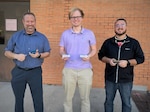 (left to right) Naval Surface Warfare Center Panama City Division (NSWC PCD) Hydrospace Laboratory Manager Dr. Christopher Musto, Hydrospace Laboratory Mechanical Engineer Jake Moody V, and Additive Manufacturing Lab (AML) Head Chuck Self stand with the various prototypes of their innovation called the Laptop Lifter (aka the Tide Riser) on Feb. 9. NSWC PCD's Codes E15 Hydrospace Laboratory and E42 Additive Manufacturing Lab (AML) collaborated to produce this solution to help improve ventilation to the division's new computers to keep them from overheating due to prolonged use. (U.S. Navy photo by Jeremy Roman)