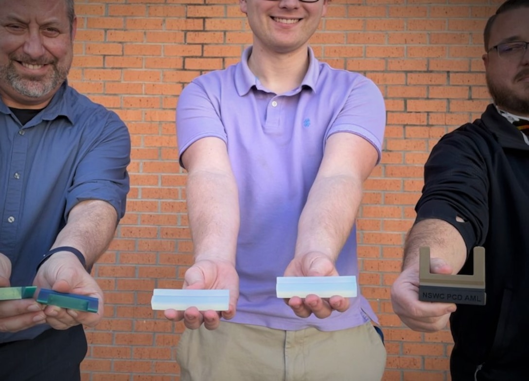 (left to right) Naval Surface Warfare Center Panama City Division (NSWC PCD) Hydrospace Laboratory Manager Dr. Christopher Musto, Hydrospace Laboratory Mechanical Engineer Jake Moody V, and Additive Manufacturing Lab (AML) Head Chuck Self stand with the various prototypes of their innovation called the Laptop Lifter (aka the Tide Riser) on Feb. 9. NSWC PCD's Codes E15 Hydrospace Laboratory and E42 Additive Manufacturing Lab (AML) collaborated to produce this solution to help improve ventilation to the division's new computers to keep them from overheating due to prolonged use. (U.S. Navy photo by Jeremy Roman)