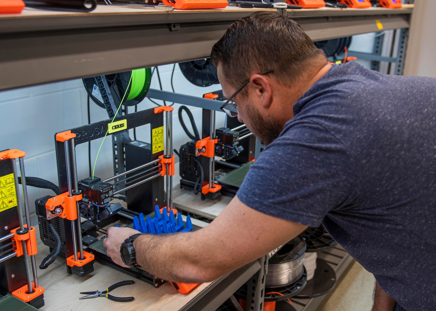 Additive Manufacturing Lab (AML) Head Chuck Self produces an innovation called the Laptop Lifter (aka the Tide Riser) engineered to extend the life of essential computer systems through improved cooling ventilation at Naval Surface Warfare Center Panama City Division on Feb. 9. Self can produce up to 240 units per day utilizing 10 or more Fused Deposition Modeling 3-D Printers. (U.S. Navy photo by Eddie Green)